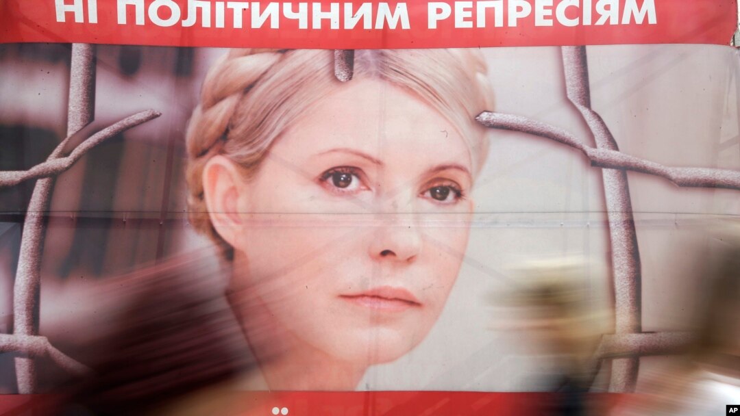 People pass by a poster of Ukraine's imprisoned former prime minister Yulia Tymoshenko at a tent camp of her supporters in central Kyiv, Ukraine, in this April 30, 2013, file photo. The text on top reads: "No to political repressions."