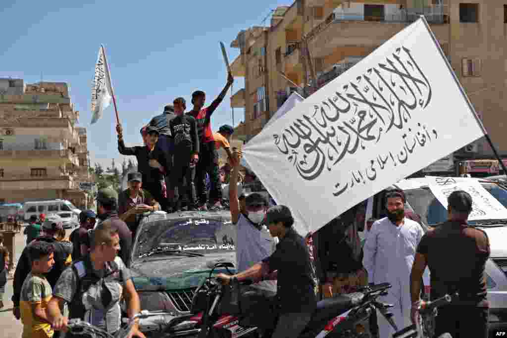 Members of Syria's top jihadist group the Hayat Tahrir al-Sham alliance, led by al-Qaida's former Syria affiliate, parade with their flags and those of the Taliban's declared "Islamic Emirate of Afghanistan" through the rebel-held northwestern city of Idl