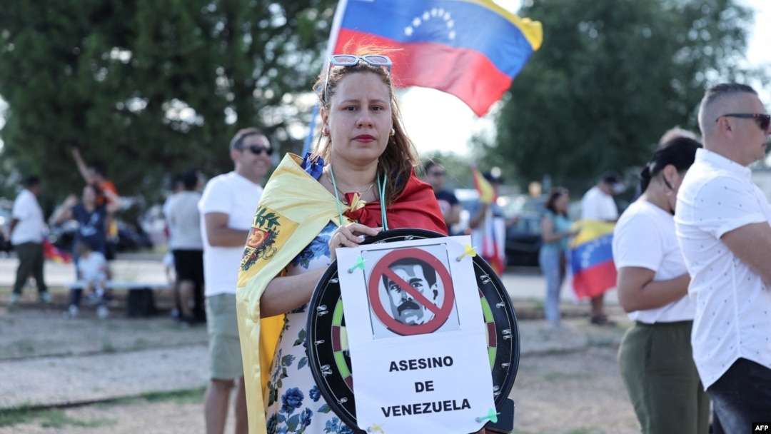 A supporter holds a sign reading '[current Venezuela's President Nicolas Maduro] murderer of Venezuela', upon the arrival of Edmundo Gonzalez Urrutia at Madrid's Torrejon de Ardoz military airport, Sept. 8, 2024.