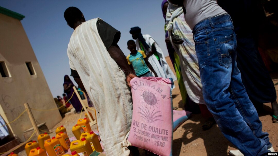 FILE - A man walks away with a bag of rice at a food distribution center run by the Spanish NGO Accion Contra el Hambre (Action Against Hunger) in Tarenguel, Mauritania, May 30, 2012.