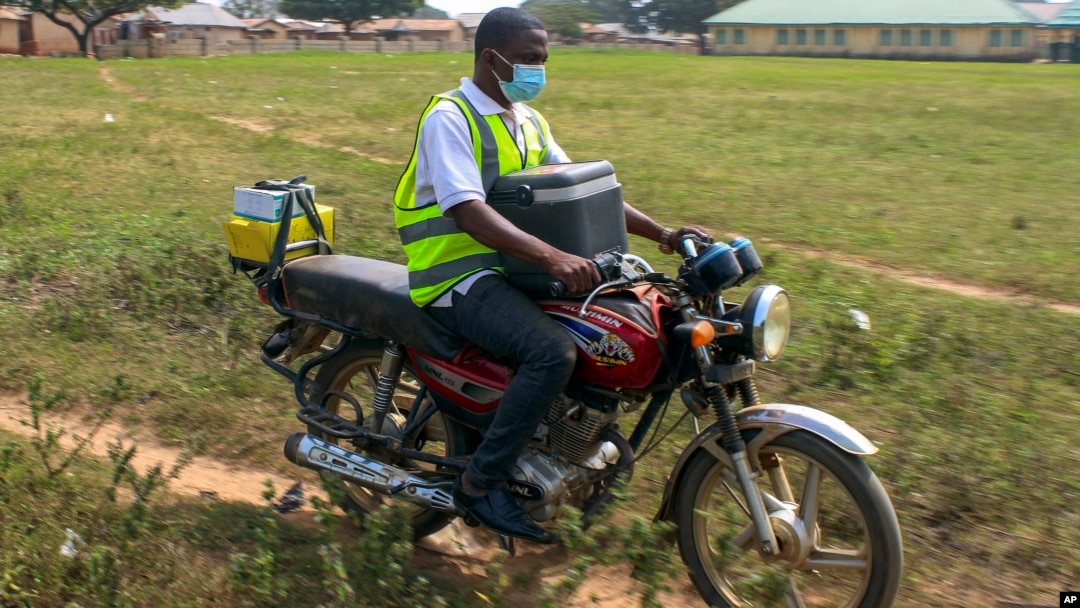 Yunusa Bawa, a community health worker, rides on a motorbike with a box of AstraZeneca coronavirus vaccines, in Sabon Kuje on the outskirts of Abuja, Nigeria, Dec 6, 2021.