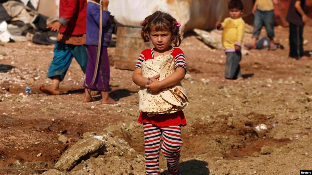 FILE - A girl carries bread outside the tents in the Bab Al-Salam refugee camp in Azaz, Oct. 27, 2014.