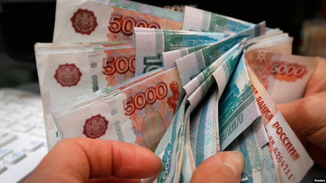 FILE - An employee counts Russian rouble banknotes at a shop in Krasnoyarsk, Dec. 26, 2014. 