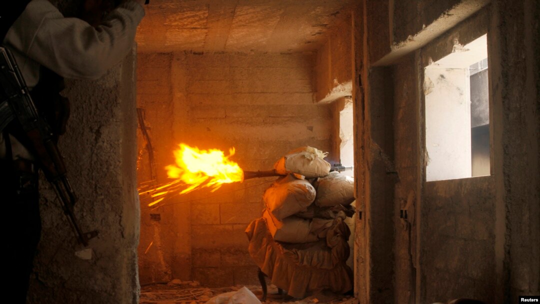 Free Syrian Army fighters take cover while firing a rocket on the front line in Izaa district in Aleppo Feb. 24, 2013. 
