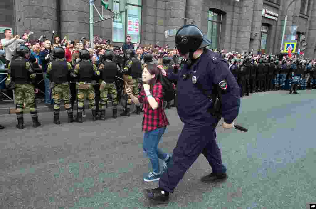 A Russian police officer detains a teenager during rally protesting retirement age hikes in St. Petersburg.