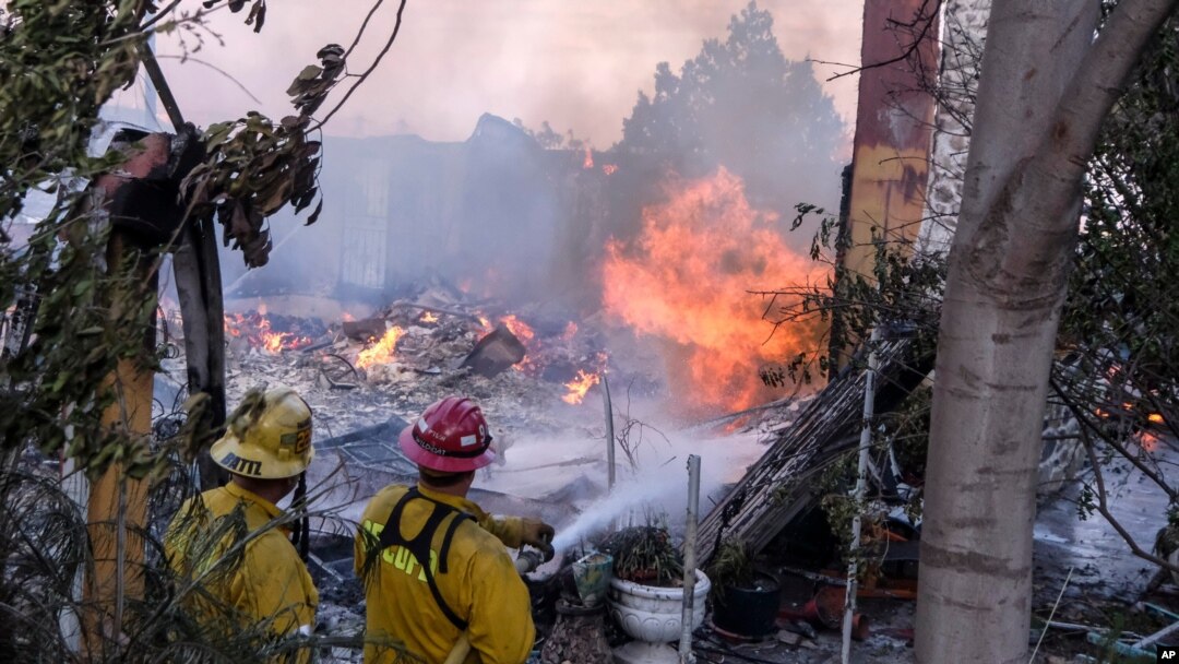 Firefighters try to extinguish the flames at a burning house as the South Fire burns in Lytle creek, San Bernardino County north of Rialto, Calif., Aug. 25, 2021.