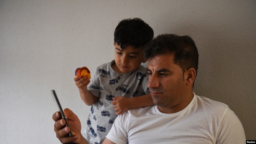 FILE - Special Immigrant Visa Afghan Abdul Aman Sediqi, a U.S. Special Immigrant Visa (SIV) recipient, and his son Elyan watch news from Kabul following their evacuation from Afghanistan in Houston, Texas, Aug 26, 2021. 