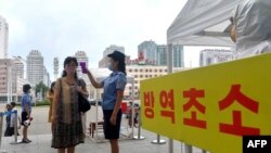 지난해 8월 북한 평양역 입구에서 역무원이 신종 코로나바이러스 방역을 위해 승객들의 체온을 재고 있다. 