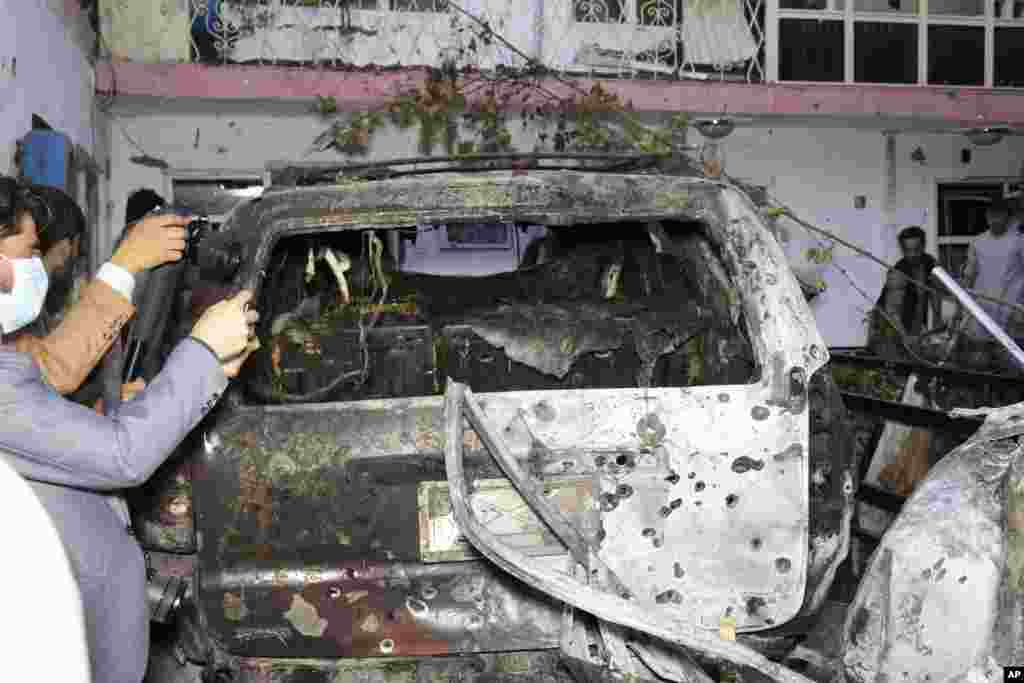 Afghan journalists take a photos of destroyed vehicle inside a house after U.S. drone strike in Kabul. A U.S. drone strike destroyed a vehicle carrying "multiple suicide bombers" from Afghanistan's Islamic State affiliate before they could attack the ongoing military evacuation at Kabul's international airport, American officials said.