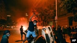 Manifestantes vandalizan un automóvil durante protestas por la muerte de George Flyod, el domingo 31 de mayo de 2020 en Washington, D.C.