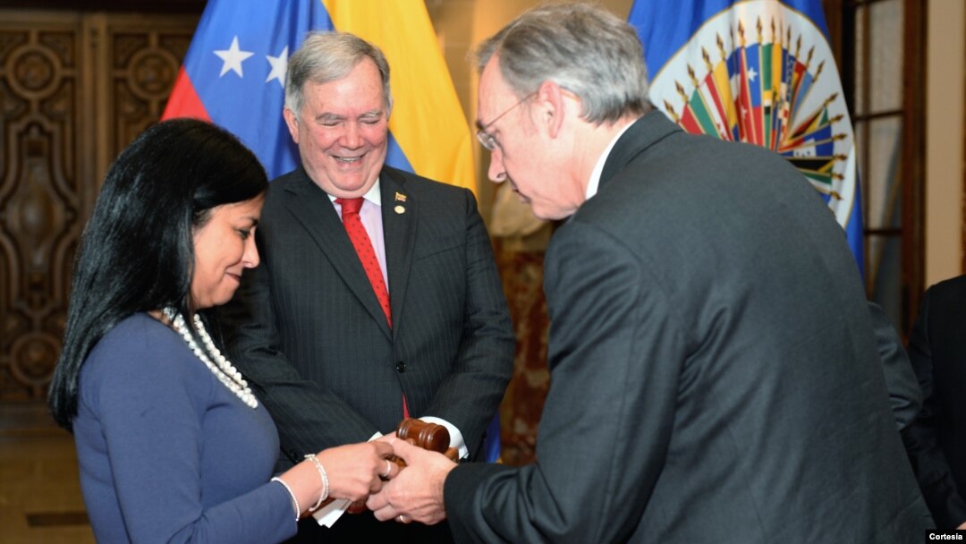 La canciller venezolana recibe el mallet de manos del embajador uruguayo, Hugo Cayrús. Atrás, embajador Roy Chaderton.