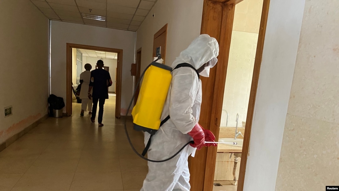 FILE - A health agent wearing protective equipment disinfects the corridors amid the spread of the coronavirus, at an hospital in Douala, Cameroon, April 27, 2020.