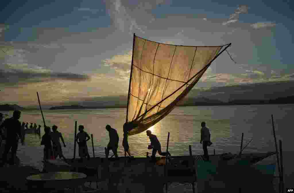 Fishermen lod their boat with fish to sell at a market at the banks of the Brahmaputra River at Ujanbazar Ghat in Guwahati, India.