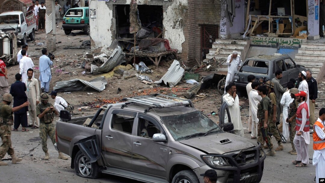 Pakistani security officials and rescue workers examine the site of car bombing on the outskirts of Peshawar, Pakistan, June 2013.