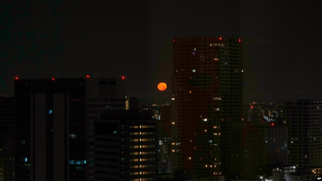 Tokyo's skyline is seen through the window of a hotel as the moon sets on July 23, 2021, in Tokyo. The opening ceremonies for the 2020 Summer Olympics are set for Friday.