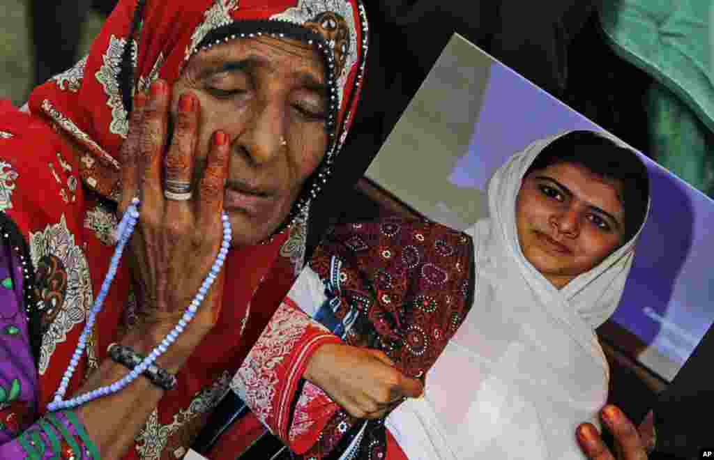 A supporter of Pakistani political party Muttahida Qaumi Movement (MQM), reacts while holding a poster of Malala Yousufzai during a rally to condemn the attack in Karachi, Pakistan, October 14, 2012.