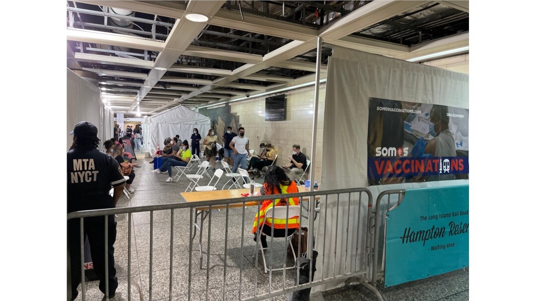 FILE - People wait to get a free COVID-19 vaccine at Penn Station, in New York City, June 8, 2021.