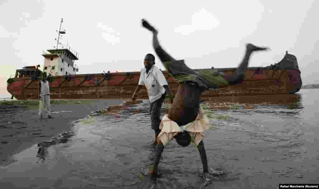 Uma criança em acrobacias na praia dos pescadores em Cabinda