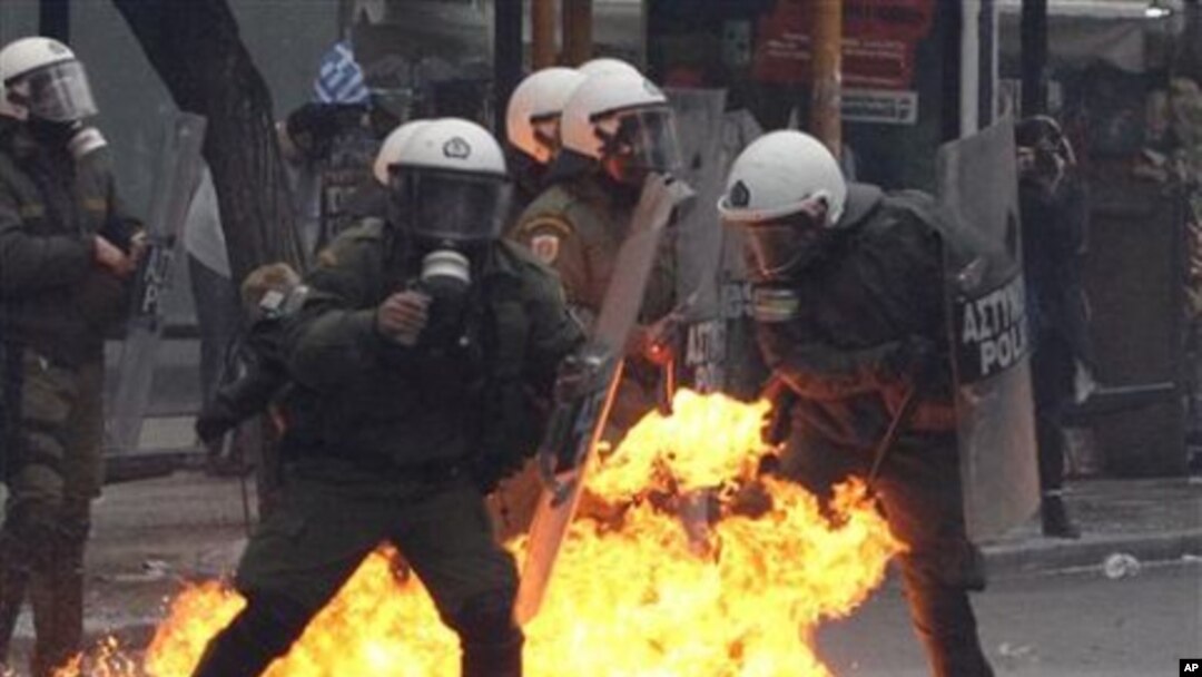 A petrol bomb explodes among riot police during clashes with protesters in Athens, 15 Dec 2010