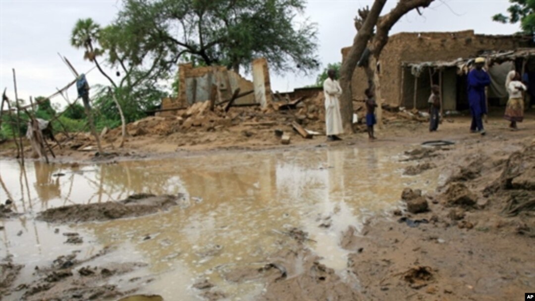 A picture released by Oxfam and taken on17 Aug 2010 shows people standing near homes destroyed by flooding near Zinder