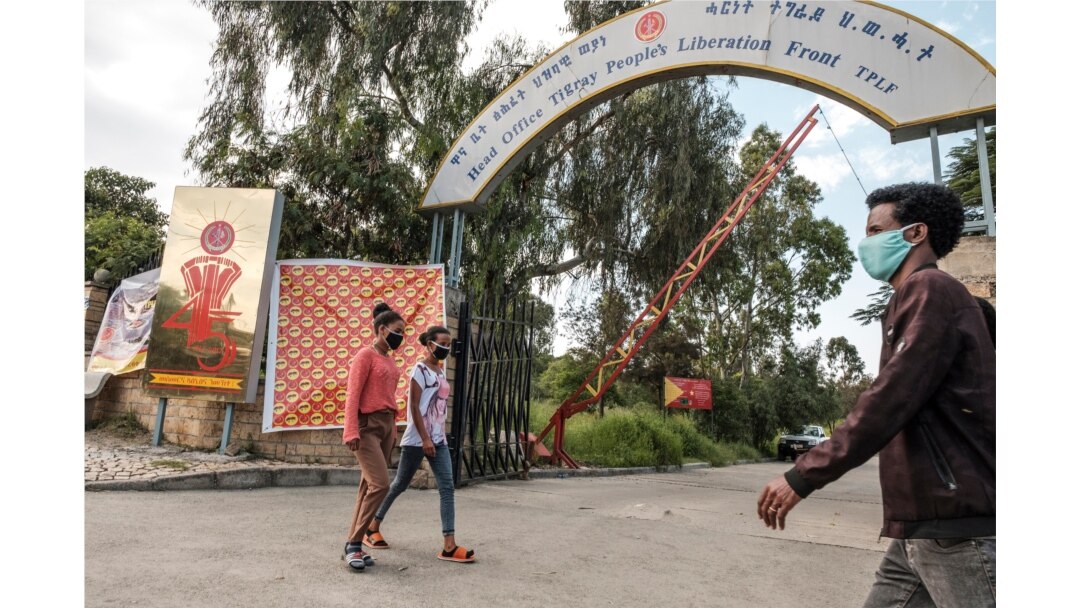 FILE - People walk in front of the head office of the Tigray People’s Liberation Front, the ruling party in the region, in the city of Mekele, northern Ethiopia, Sept. 6, 2020.