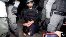 Afisa wa polisi wa Israel akimshikilia mwanadamanaji wa Palestina wakati wa maadamano kabla ya Mahakama kutoa uamuzi wa kuchukuliwa makazi ya familia ya Wapalestina, huko eneo la Sheikh Jarrah, jirani na mashariki ya Jerusalem, Mei 5, 2021.